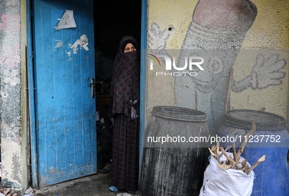 A displaced Palestinian woman is looking out of a classroom as she views the damages at the site of an Israeli strike on a school sheltering...