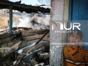 A Palestinian boy is inspecting the site of an Israeli strike on a school sheltering displaced people, amid the ongoing conflict between Isr...