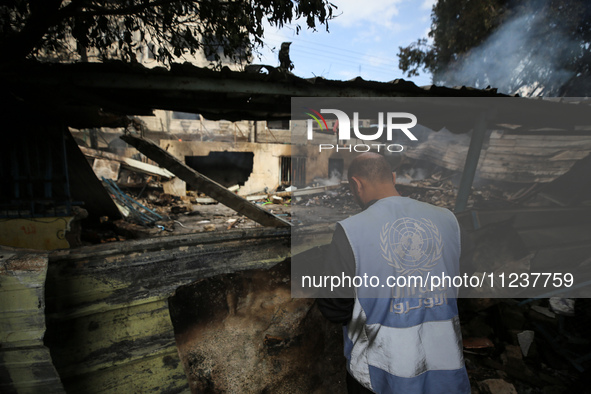 A Palestinian employee of UNRWA is looking at damages at the site of an Israeli strike on a school sheltering displaced people, amid the ong...