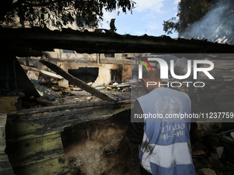 A Palestinian employee of UNRWA is looking at damages at the site of an Israeli strike on a school sheltering displaced people, amid the ong...