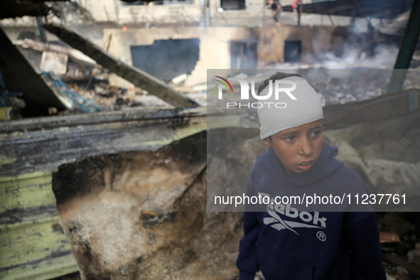 A Palestinian boy is inspecting the site of an Israeli strike on a school sheltering displaced people, amid the ongoing conflict between Isr...