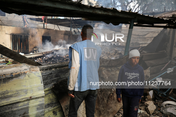 A Palestinian boy is inspecting the site of an Israeli strike on a school sheltering displaced people, amid the ongoing conflict between Isr...