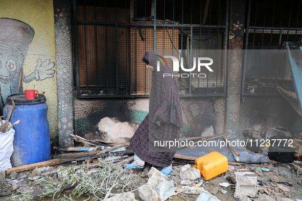 A displaced Palestinian woman is looking out of a classroom as she views the damages at the site of an Israeli strike on a school sheltering...