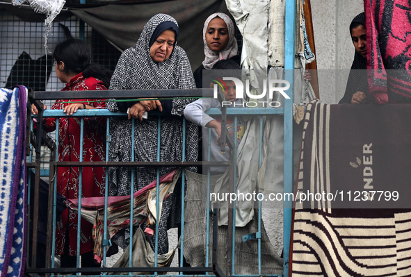 Palestinian women are looking on at the site of an Israeli strike on a school sheltering displaced people, amid the ongoing conflict between...