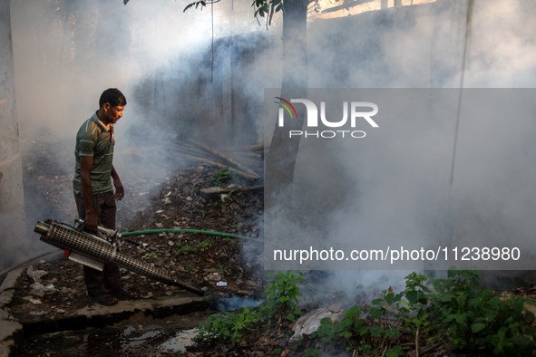 A worker is spraying pesticide to kill mosquitoes as a preventive measure against Dengue fever in a densely populated residential area in Dh...