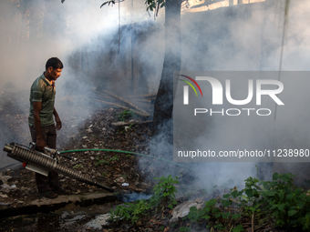 A worker is spraying pesticide to kill mosquitoes as a preventive measure against Dengue fever in a densely populated residential area in Dh...