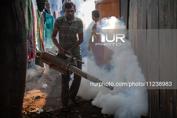 A worker is spraying pesticide to kill mosquitoes as a preventive measure against Dengue fever in a densely populated residential area in Dh...