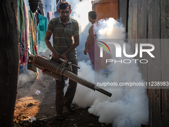 A worker is spraying pesticide to kill mosquitoes as a preventive measure against Dengue fever in a densely populated residential area in Dh...