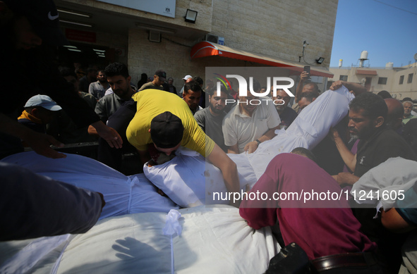 A man is carrying the shrouded body of a child, killed in an overnight Israeli strike on the Al-Breij refugee camp, during a mass funeral at...