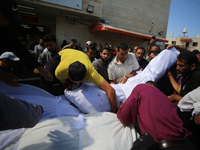 A man is carrying the shrouded body of a child, killed in an overnight Israeli strike on the Al-Breij refugee camp, during a mass funeral at...