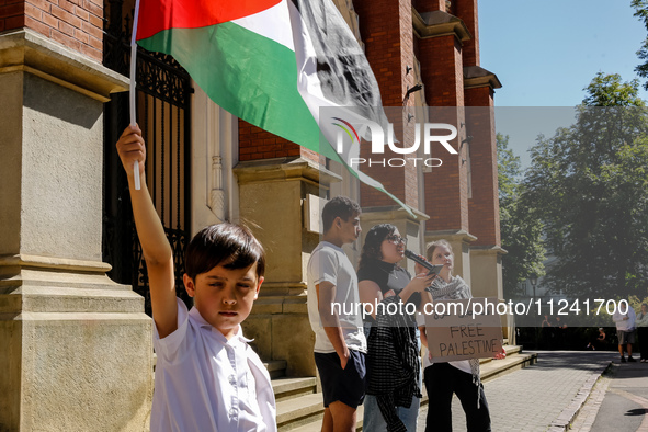 Palestinian boyhold a flag as Hansa, a young men who fled Gaza 10 days ago (second left) speaks during academia demonstration against Israel...