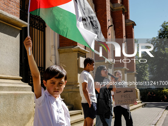 Palestinian boyhold a flag as Hansa, a young men who fled Gaza 10 days ago (second left) speaks during academia demonstration against Israel...