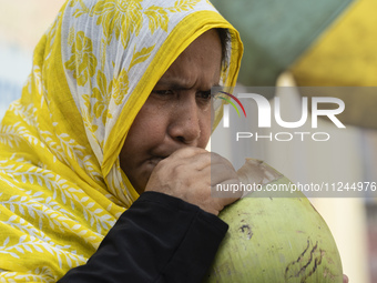 People are drinking coconut water along the roadside on a hot summer day in Guwahati, Assam, India, on May 16, 2024. Coconut water is natura...