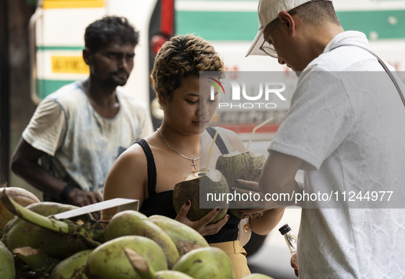 People are drinking coconut water along the roadside on a hot summer day in Guwahati, Assam, India, on May 16, 2024. Coconut water is natura...