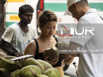 People are drinking coconut water along the roadside on a hot summer day in Guwahati, Assam, India, on May 16, 2024. Coconut water is natura...