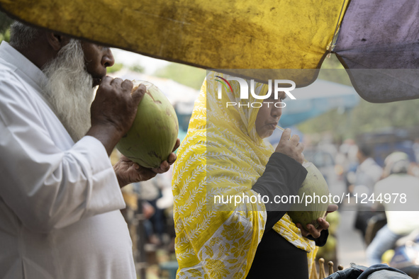 People are drinking coconut water along the roadside on a hot summer day in Guwahati, Assam, India, on May 16, 2024. Coconut water is natura...