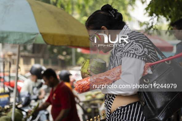 People are drinking coconut water along the roadside on a hot summer day in Guwahati, Assam, India, on May 16, 2024. Coconut water is natura...