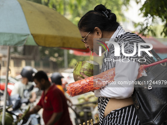 People are drinking coconut water along the roadside on a hot summer day in Guwahati, Assam, India, on May 16, 2024. Coconut water is natura...