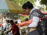 People are drinking coconut water along the roadside on a hot summer day in Guwahati, Assam, India, on May 16, 2024. Coconut water is natura...