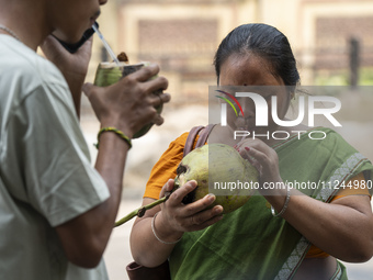 People are drinking coconut water along the roadside on a hot summer day in Guwahati, Assam, India, on May 16, 2024. Coconut water is natura...