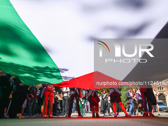 Students and activists hold a huge Palestinian flag during  solidarity with Palestine demonstration in front of Jagiellonian University buil...