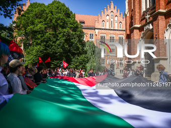 Students and activists hold a huge Palestinian flag during  solidarity with Palestine demonstration in front of Jagiellonian University buil...