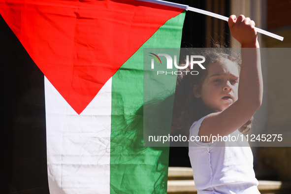 A girl holds Palestinian flag during solidarity with Palestine demonstration in front of Jagiellonian University building in Krakow, Poland...