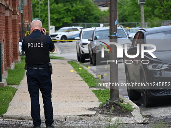 A police officer is photographing evidence at the crime scene. A 26-year-old male victim is injured in a shooting in Chicago, Illinois, Unit...