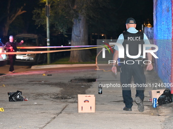 A police officer is walking through the crime scene. Three people are shot, with one person in critical condition in Chicago, Illinois, Unit...