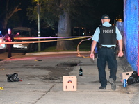 A police officer is walking through the crime scene. Three people are shot, with one person in critical condition in Chicago, Illinois, Unit...