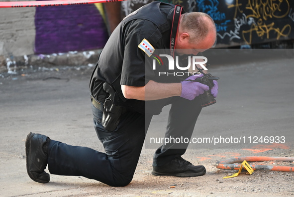 A police officer is taking a photograph of a shell casing at the crime scene. A 31-year-old male is in critical condition after attempting t...