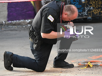 A police officer is taking a photograph of a shell casing at the crime scene. A 31-year-old male is in critical condition after attempting t...