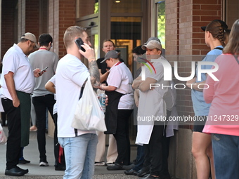 Workers of Eataly are gathering outside, wondering what is happening. There is a large police presence after an assault at Eataly Italian Re...