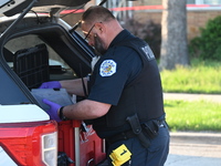 A police officer is placing evidence markers and collecting equipment at the residence where the homicide is occurring. A 54-year-old male v...