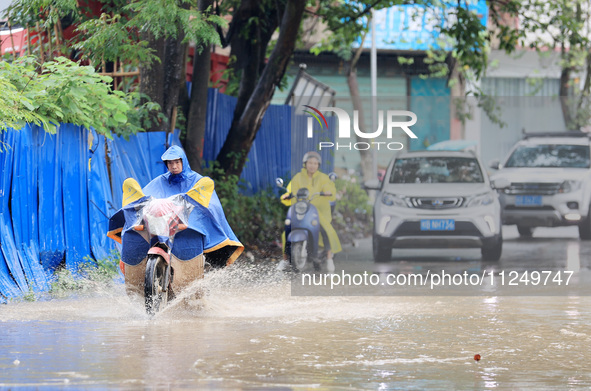 People are driving through a flooded urban road in the rain on Xinxing Road in Rongan county, Liuzhou city, South China's Guangxi Zhuang Aut...