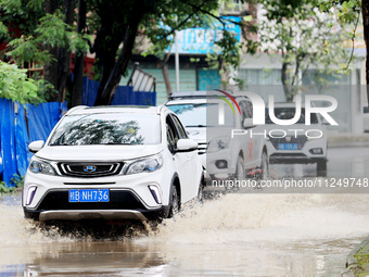 People are driving through a flooded urban road in the rain on Xinxing Road in Rongan county, Liuzhou city, South China's Guangxi Zhuang Aut...