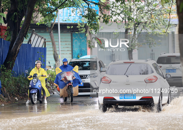 People are driving through a flooded urban road in the rain on Xinxing Road in Rongan county, Liuzhou city, South China's Guangxi Zhuang Aut...