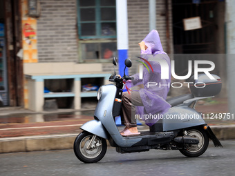 A citizen is riding in the rain on Xinxing Road in Rongan county, Liuzhou city, South China's Guangxi Zhuang Autonomous region, on May 18, 2...