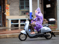 A citizen is riding in the rain on Xinxing Road in Rongan county, Liuzhou city, South China's Guangxi Zhuang Autonomous region, on May 18, 2...