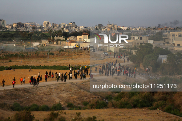 Palestinians are walking towards trucks transporting aid that is being delivered into Gaza through a U.S.-built pier, amid the ongoing confl...