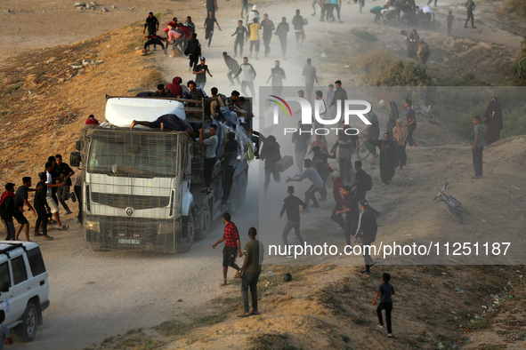 Palestinians are grabbing aid from a truck that is being delivered into Gaza through a U.S.-built pier, amid the ongoing conflict between Is...