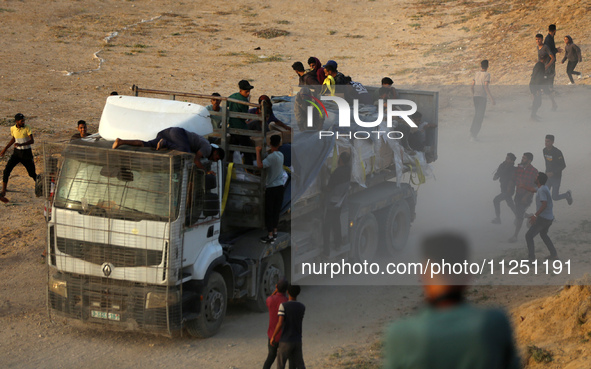 Palestinians are grabbing aid from a truck that is being delivered into Gaza through a U.S.-built pier, amid the ongoing conflict between Is...