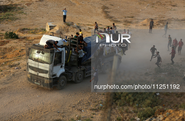 Palestinians are grabbing aid from a truck that is being delivered into Gaza through a U.S.-built pier, amid the ongoing conflict between Is...