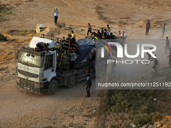 Palestinians are grabbing aid from a truck that is being delivered into Gaza through a U.S.-built pier, amid the ongoing conflict between Is...