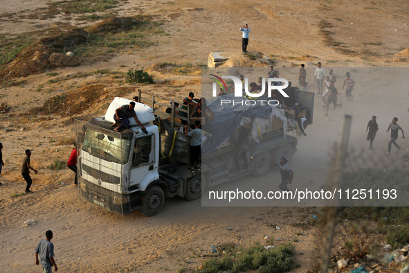 Palestinians are grabbing aid from a truck that is being delivered into Gaza through a U.S.-built pier, amid the ongoing conflict between Is...