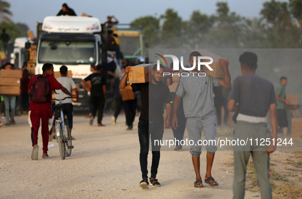 Palestinians are carrying boxes of aid that are being delivered into Gaza through a U.S.-built pier, amid the ongoing conflict between Israe...