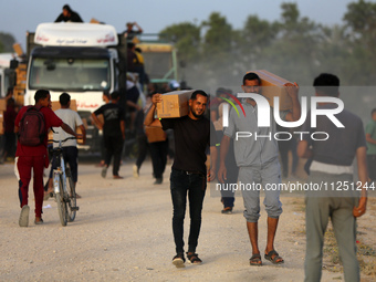 Palestinians are carrying boxes of aid that are being delivered into Gaza through a U.S.-built pier, amid the ongoing conflict between Israe...