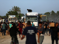 Palestinians are climbing onto trucks to grab aid that is being delivered into Gaza through a U.S.-built pier, amid the ongoing conflict bet...