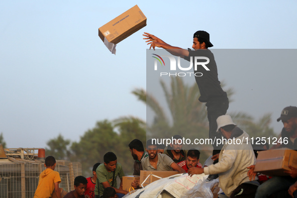 Palestinians are climbing onto trucks to grab aid that is being delivered into Gaza through a U.S.-built pier, amid the ongoing conflict bet...