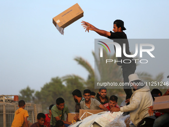 Palestinians are climbing onto trucks to grab aid that is being delivered into Gaza through a U.S.-built pier, amid the ongoing conflict bet...